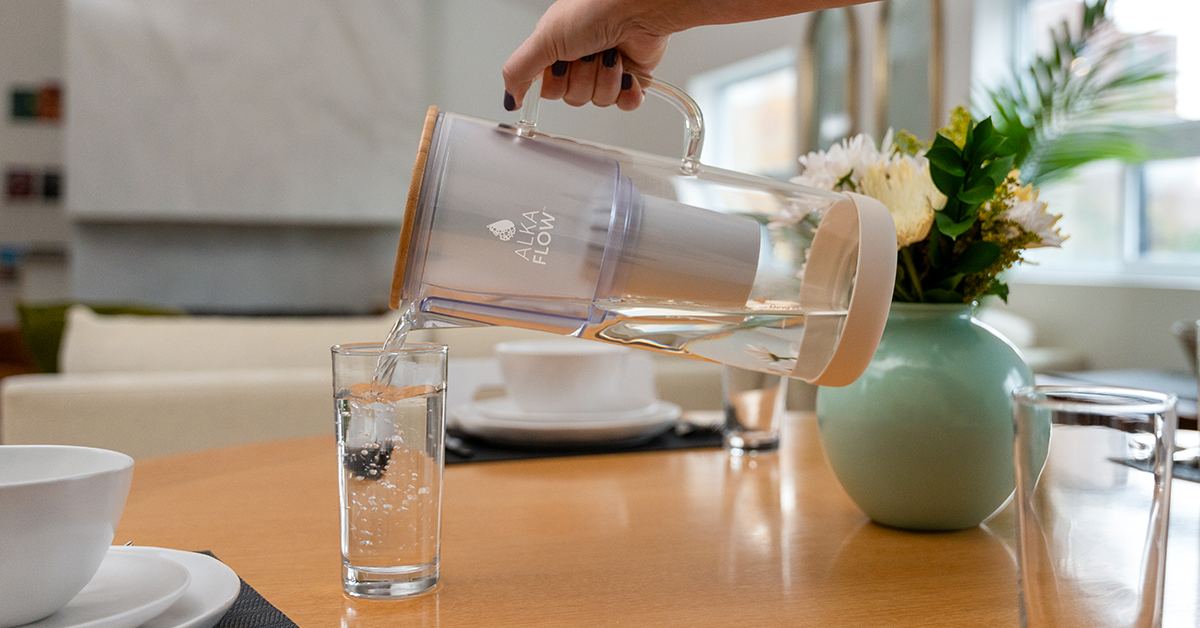 Pouring filtered water from an AlkaFlow pitcher into a glass